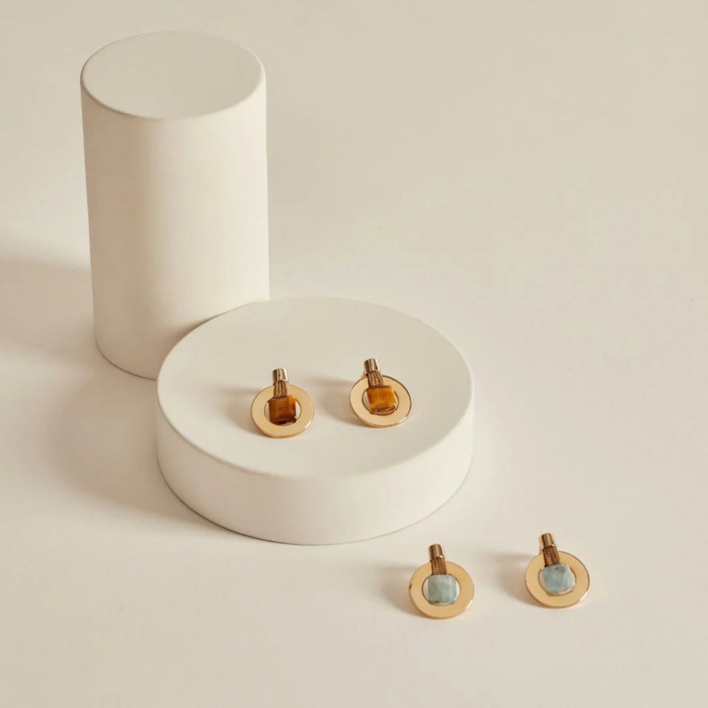 Gold earrings with circular designs on a white surface
