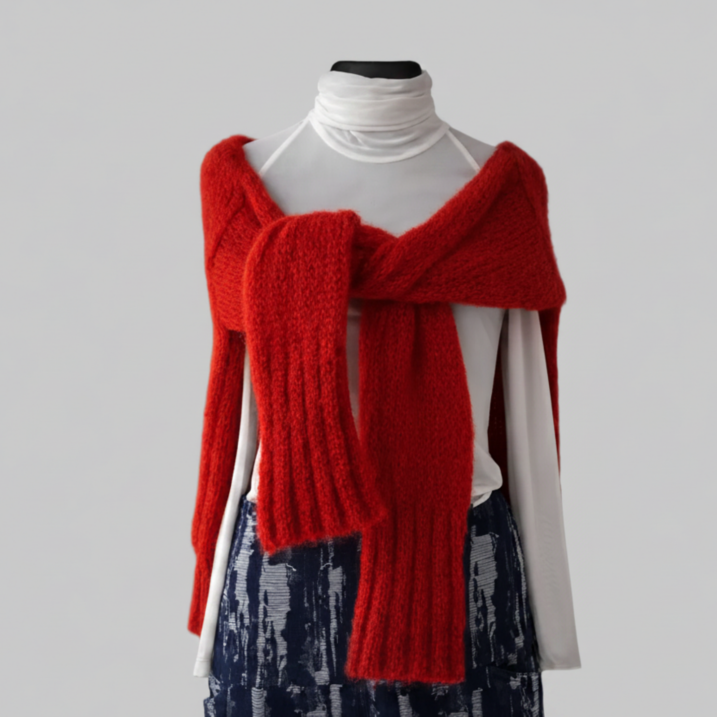 Red knitted pullover draped over the mannequin shoulders with a gray background