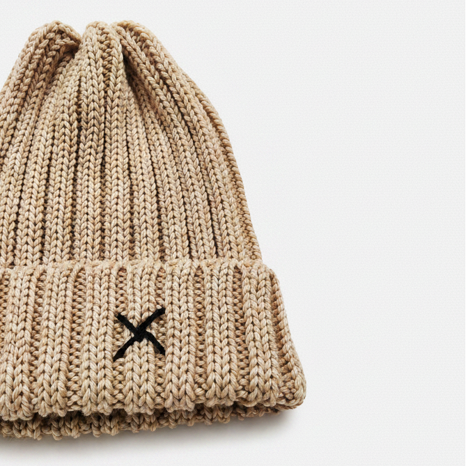 Beige knit beanie with a black logo on a white background