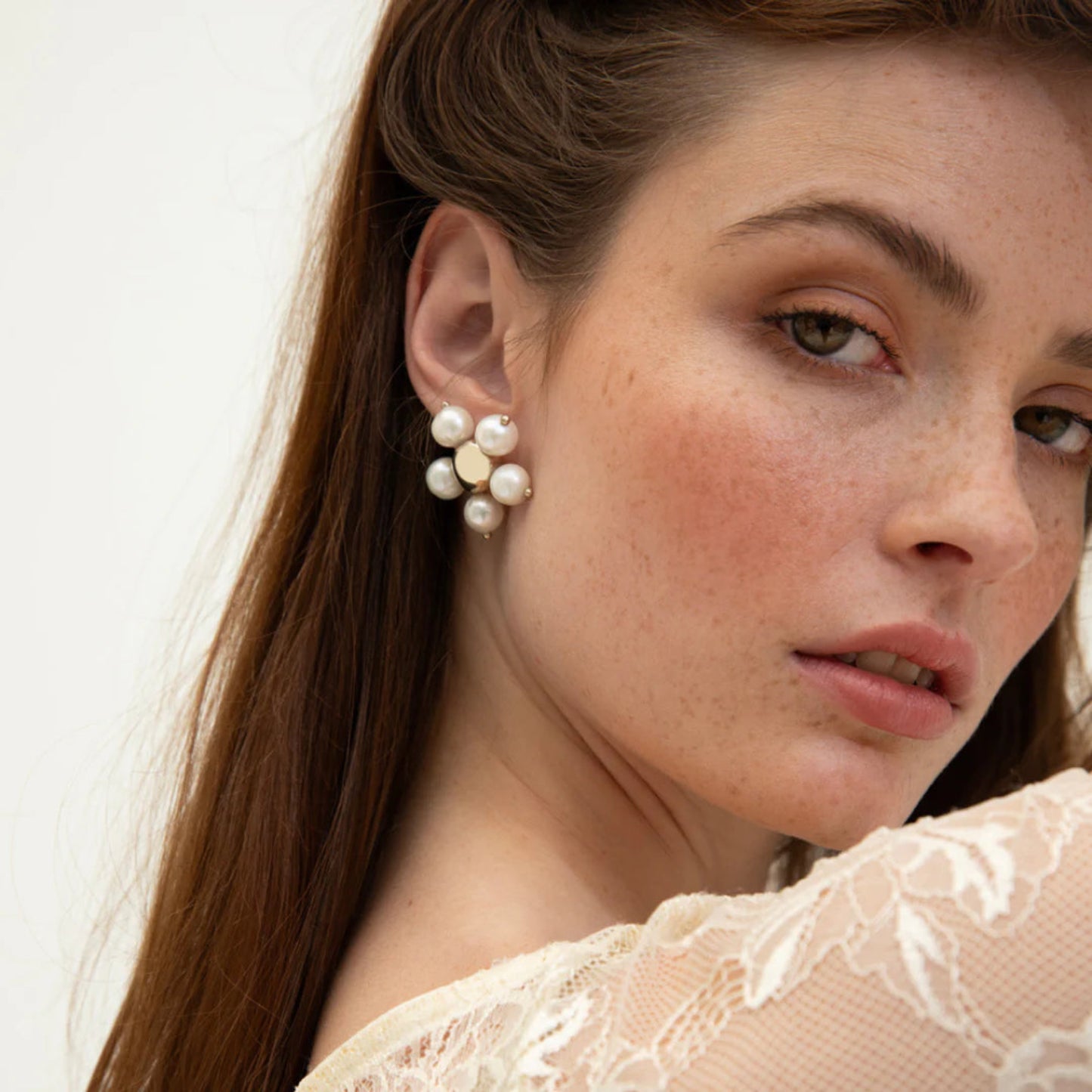 A close-up of a woman's ear wearing a silver and freshwater pearl earring.