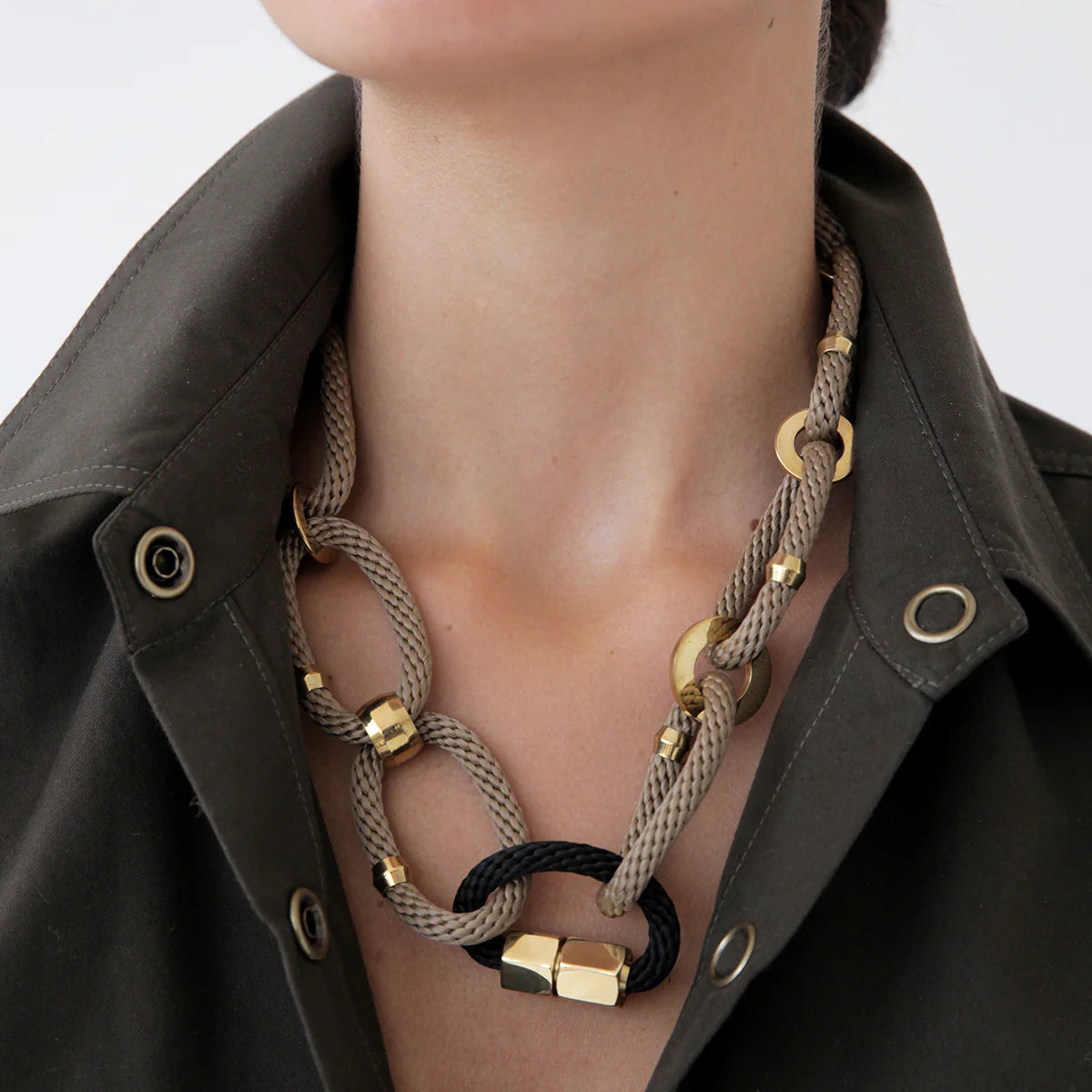 Necklace with gold and black elements worn by a person against a neutral background