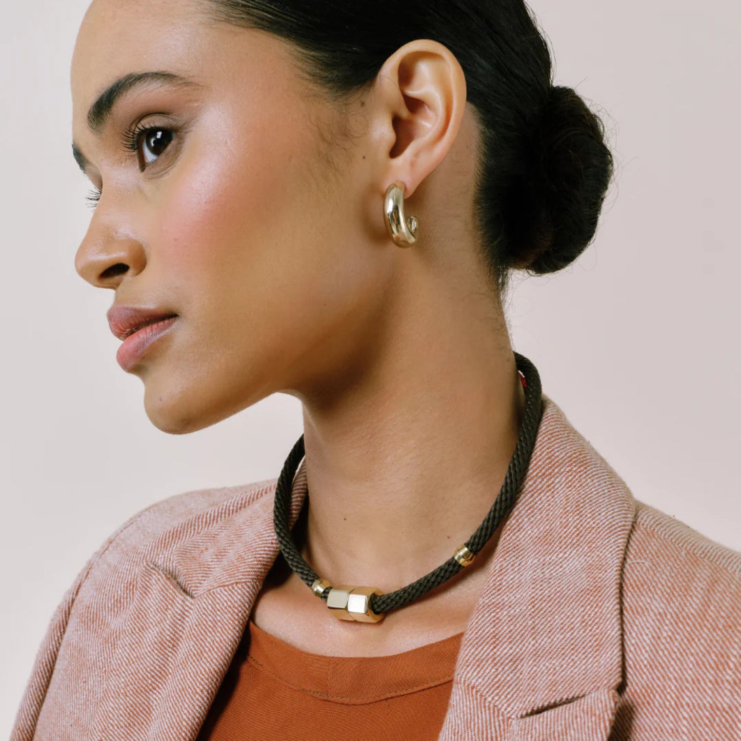 Woman wearing a necklace with gold accents on a neutral background