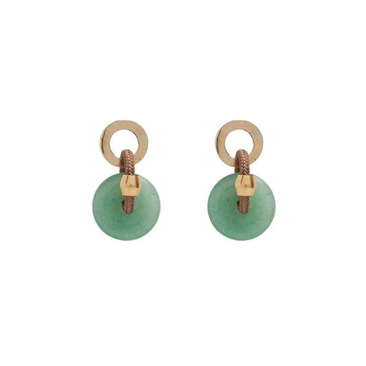 A person wearing a beige coat and green aventurine stone earrings with brass and silver studs.