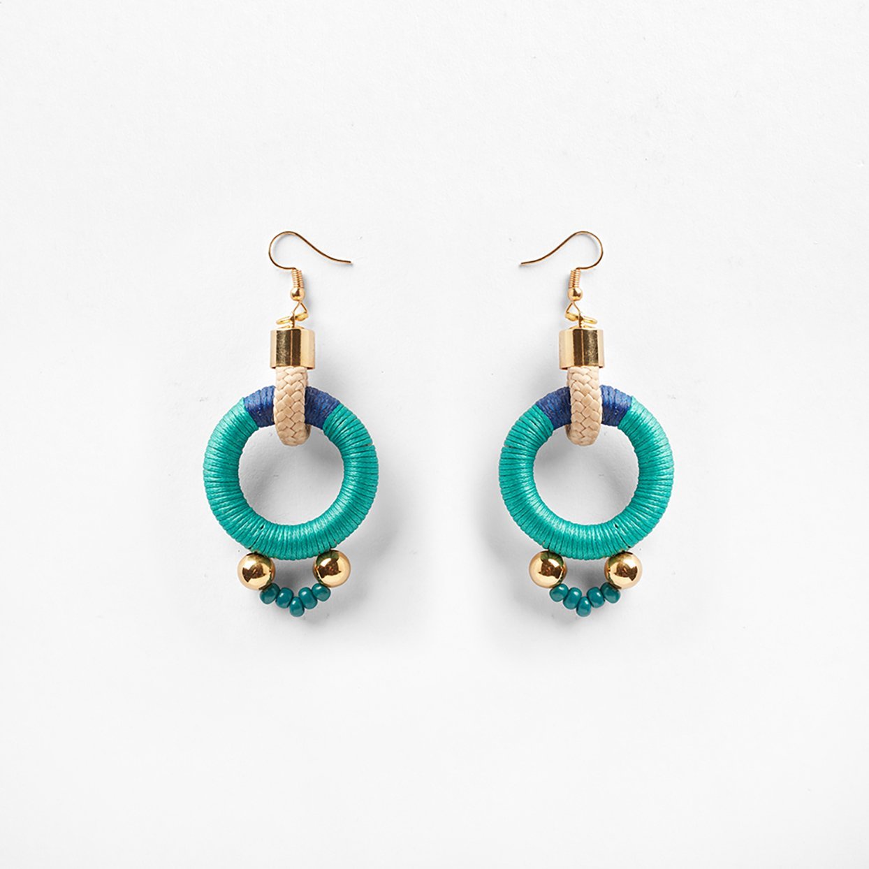 Circular blue and aqua rope earrings featuring a sleek s-hook clasp for secure fastening. The vibrant colors of blue and aqua intertwine beautifully, creating a striking visual contrast. Delicate beads embellish the bottom of the earrings, accented with shimmering gold beads that add a touch of elegance. The circular design offers a modern and versatile aesthetic, suitable for various occasions. 