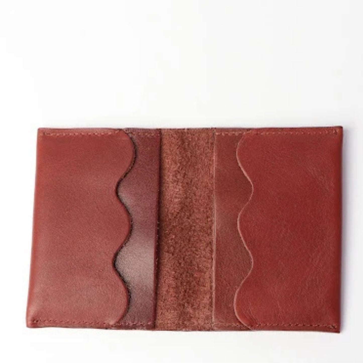 A reddish-brown leather card holder wallet shown open against a plain white background.