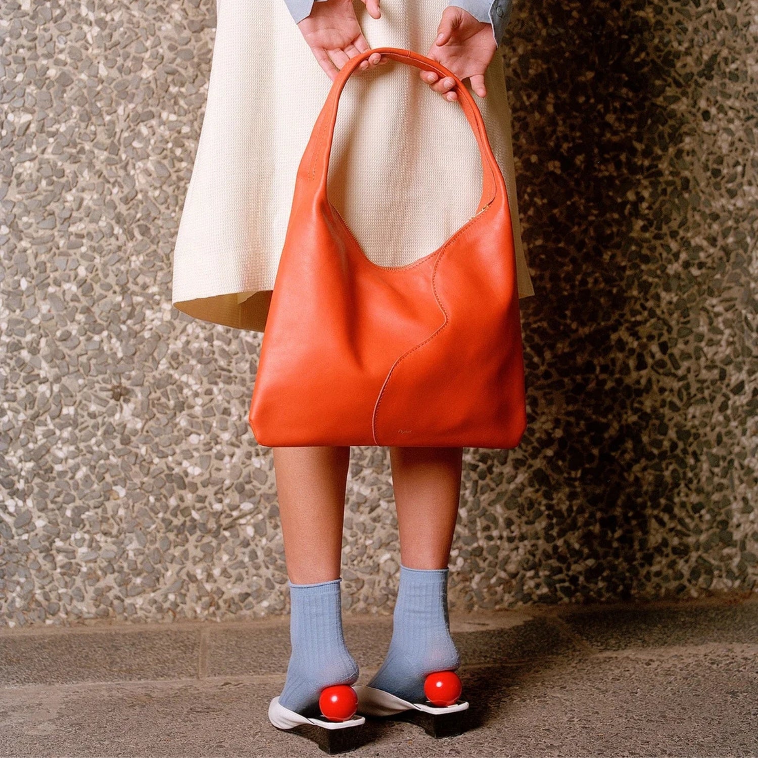 Model wearing a cream knit, grey-blue shirt and socks as a contrast colour to the Libra Lobster red.