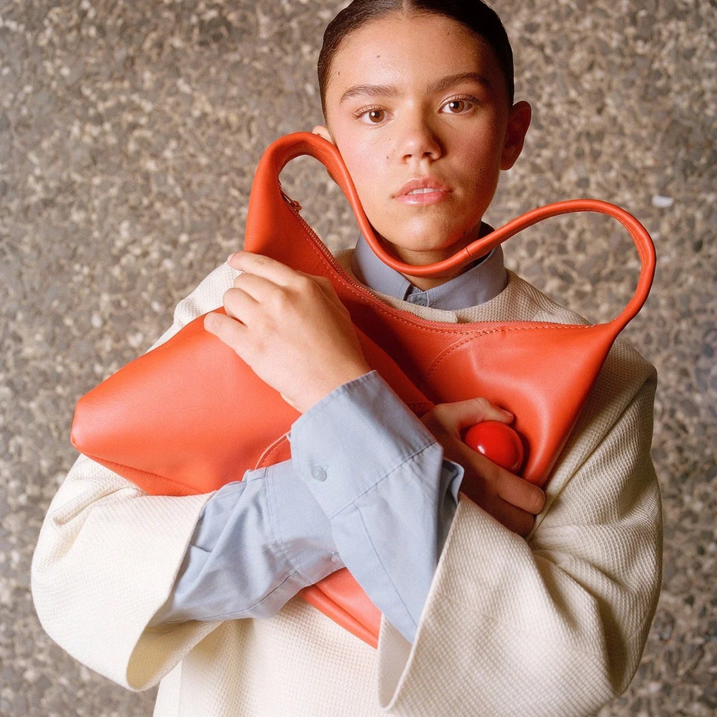 Model holding the Lobster Orange-red Libra bag close up, for sizing against her chest.