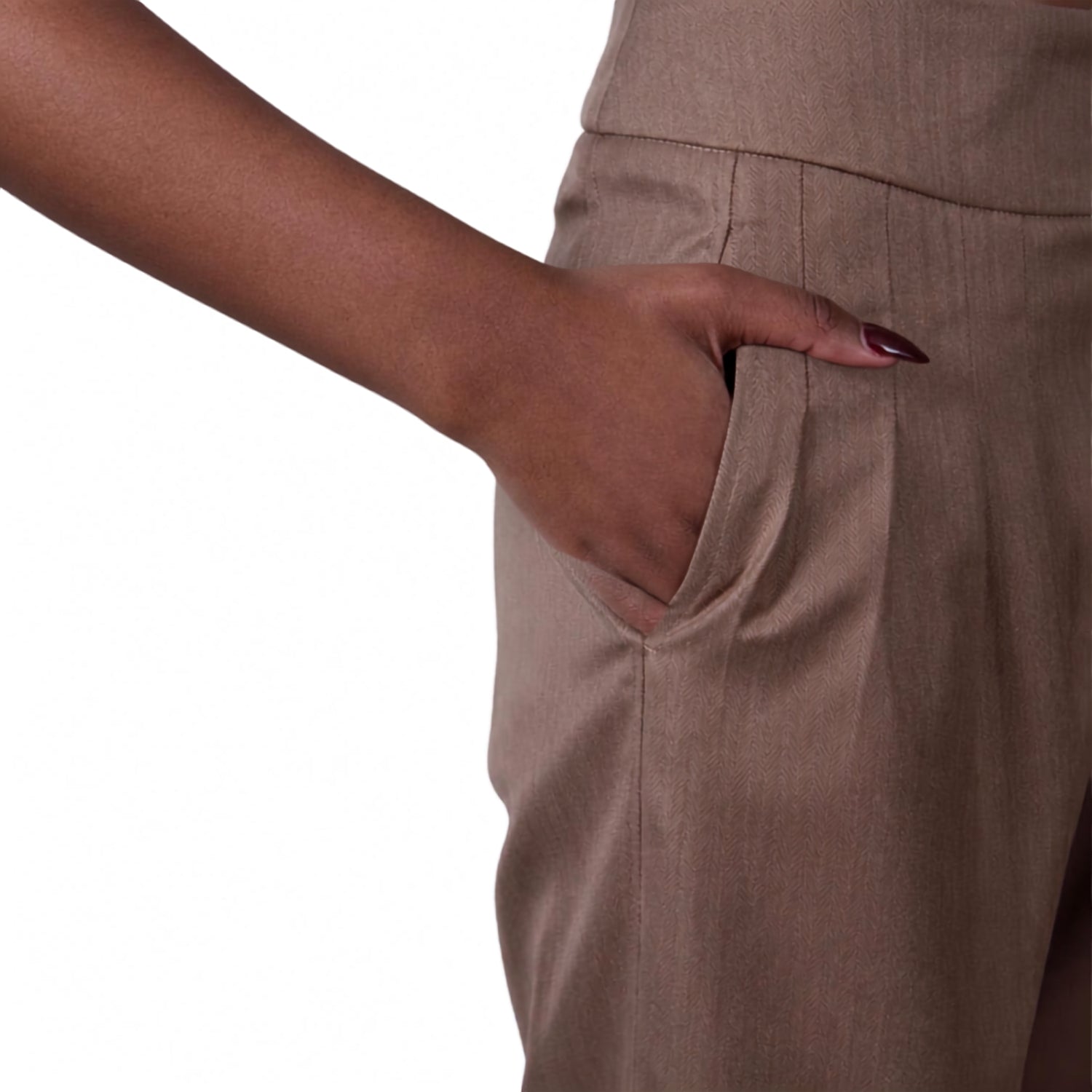 Close-up of a person wearing taupe-brown trousers, showing a hand tucked into a side pocket against a plain white background.
