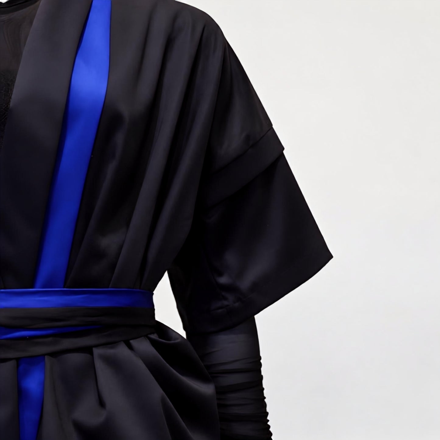 A dark navy blue kimono-style robe with vibrant royal blue stripe down the front and a matching waist tie, worn with a black sheer mesh top.