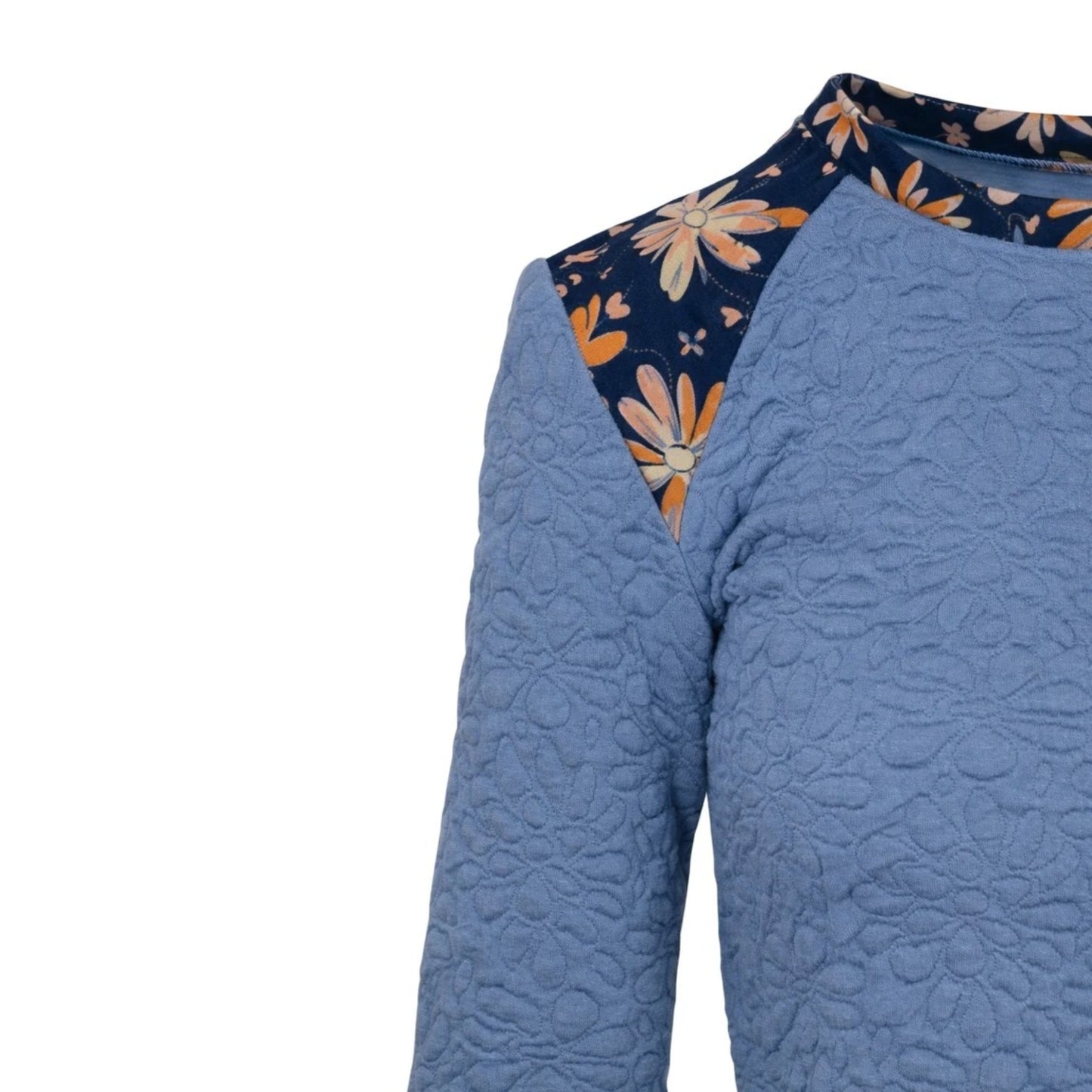 A close-up of a quilted blue top with a floral patterned yoke and collar, shown against a plain white background.