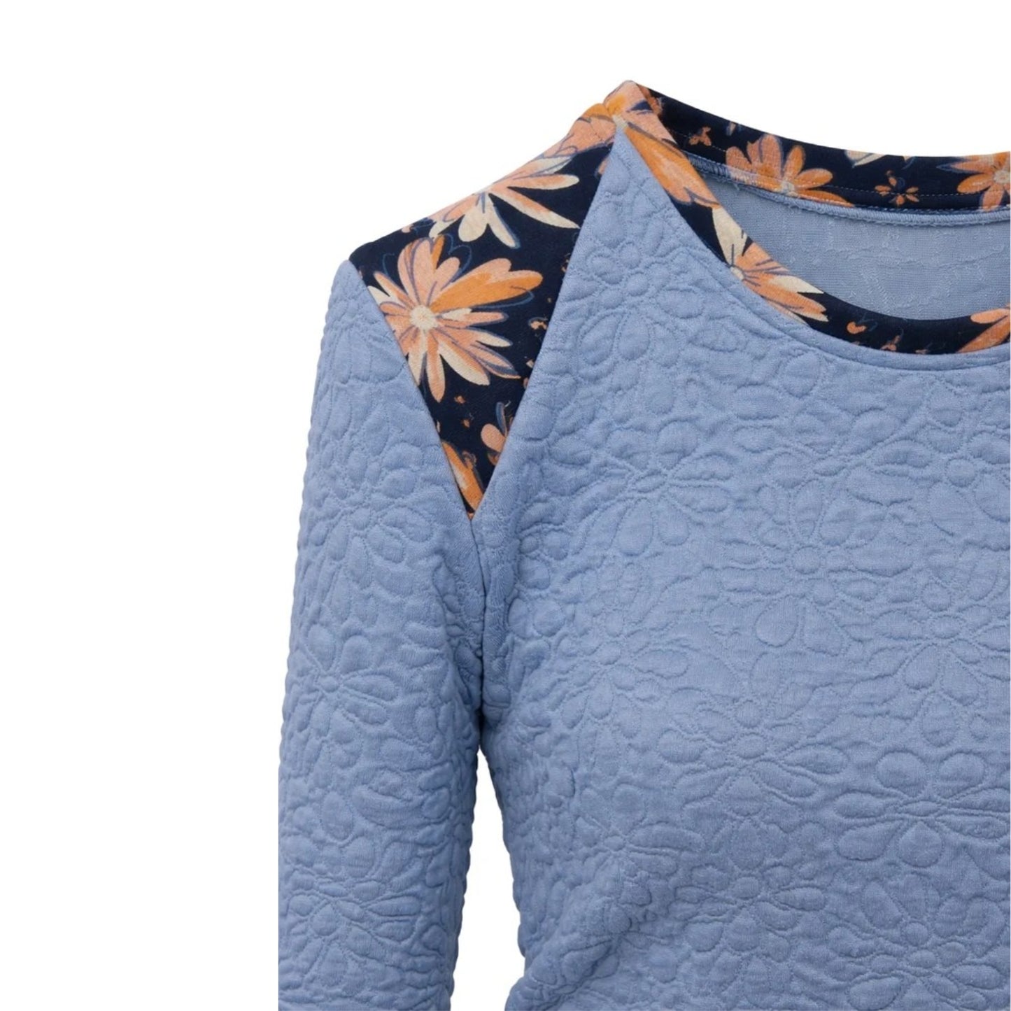 Close-up of a light blue quilted long-sleeve top with a floral-patterned yoke detail in navy, orange, and cream, shown against a plain white background.