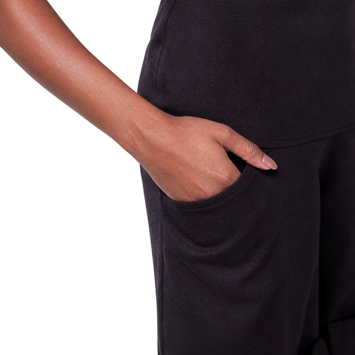 Close-up of a person wearing black wide-leg pants, showing a hand reaching into a side pocket against a plain white background.