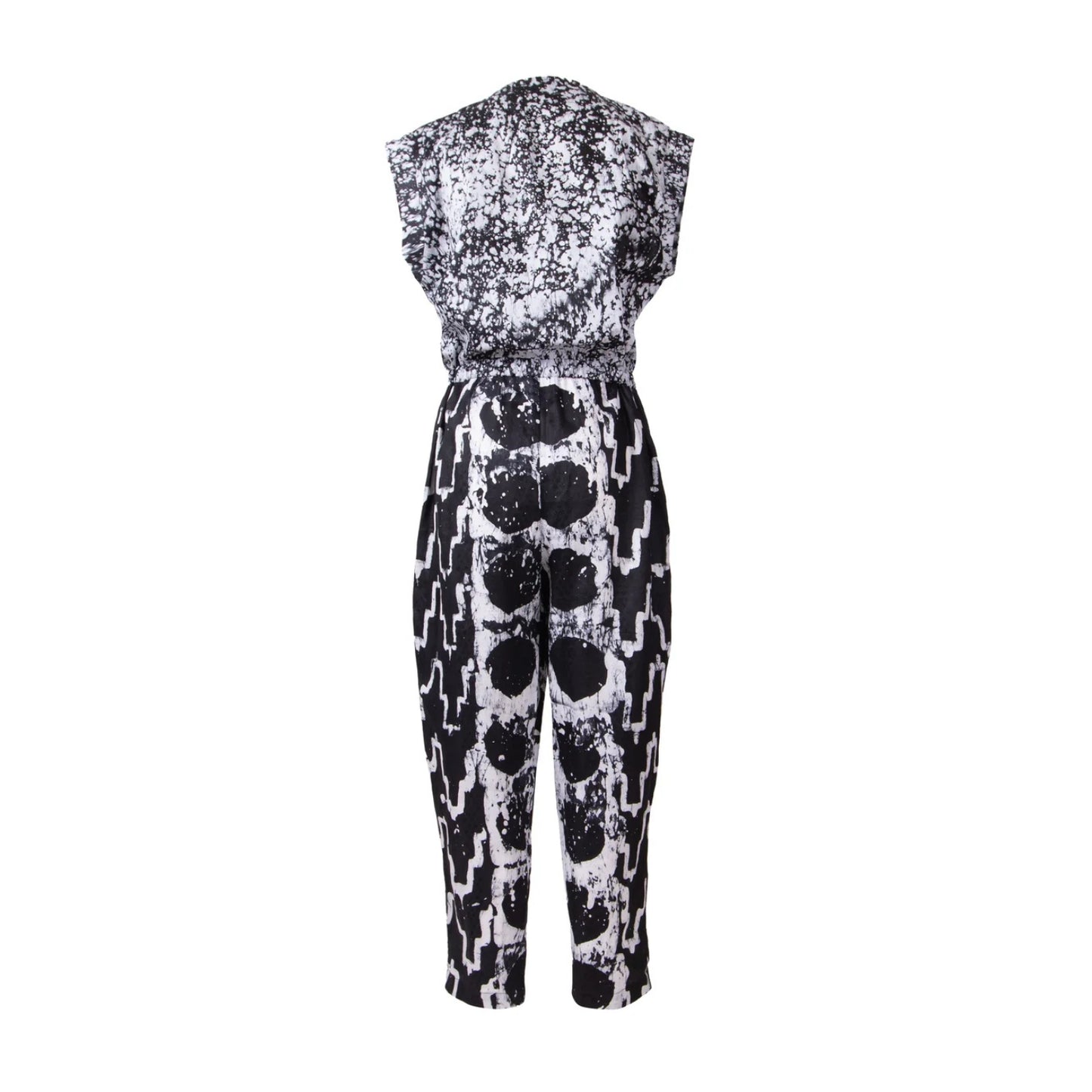 A sleeveless one-piece jumpsuit featuring a black and white abstract pattern, with a distressed splatter design on the bodice and a bold vertical stripe pattern on the legs.