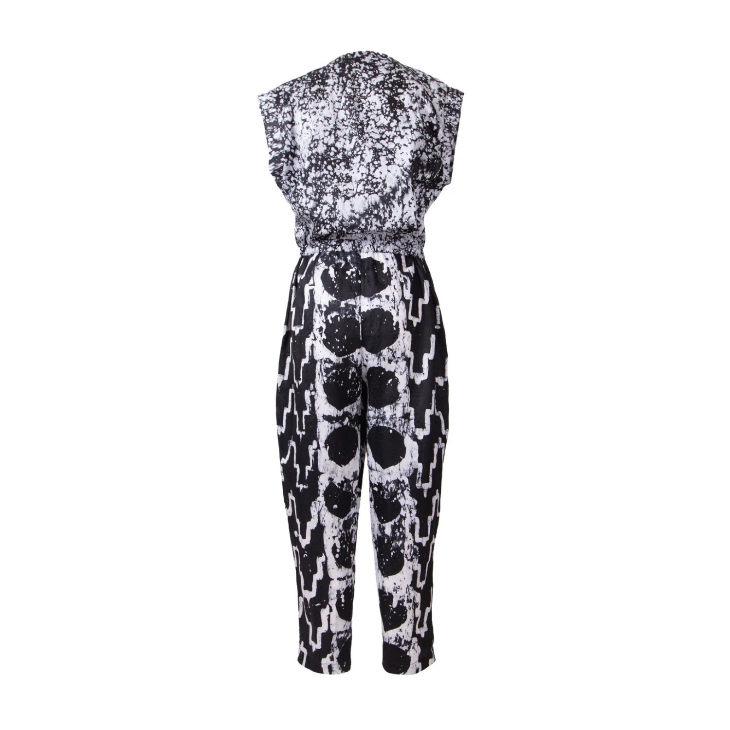 A sleeveless one-piece jumpsuit featuring a black and white abstract pattern, with a distressed splatter design on the bodice and a bold vertical stripe pattern on the legs.
