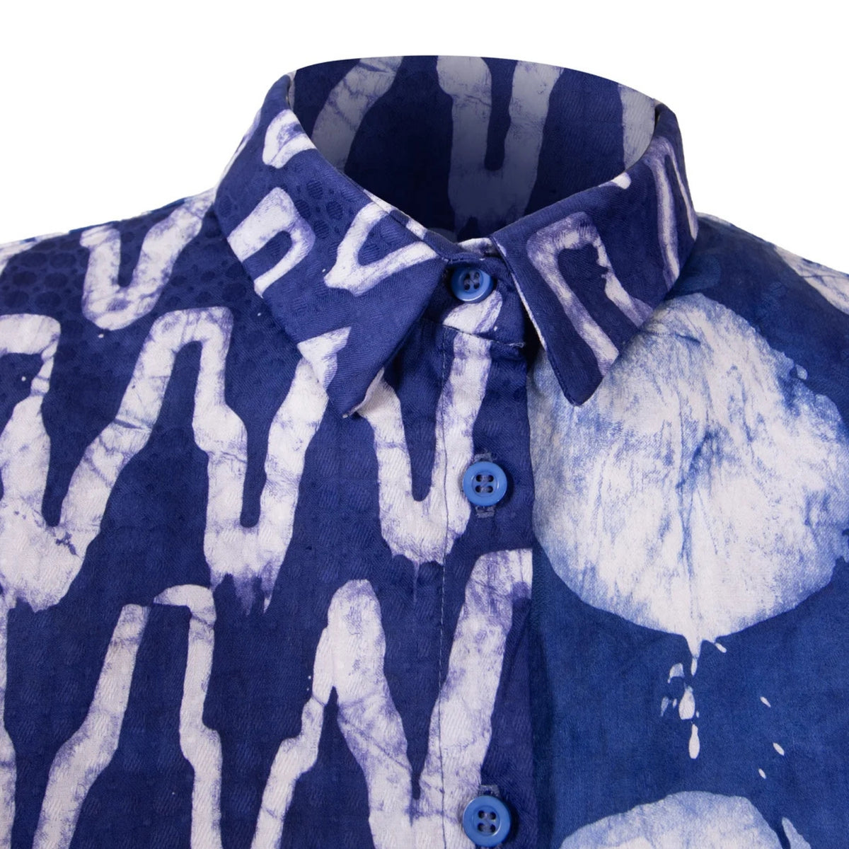 A close-up of a short-sleeve button-up shirt with a blue and white tie-dye pattern, featuring a pointed collar and blue buttons, shown against a plain white background.