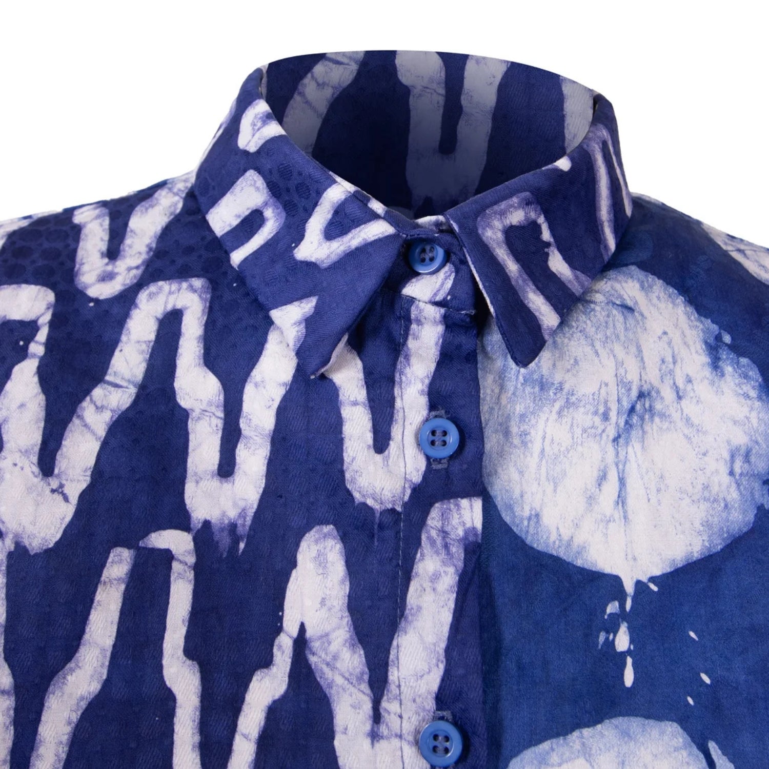 A close-up of a short-sleeve button-up shirt with a blue and white tie-dye pattern, featuring a pointed collar and blue buttons, shown against a plain white background.