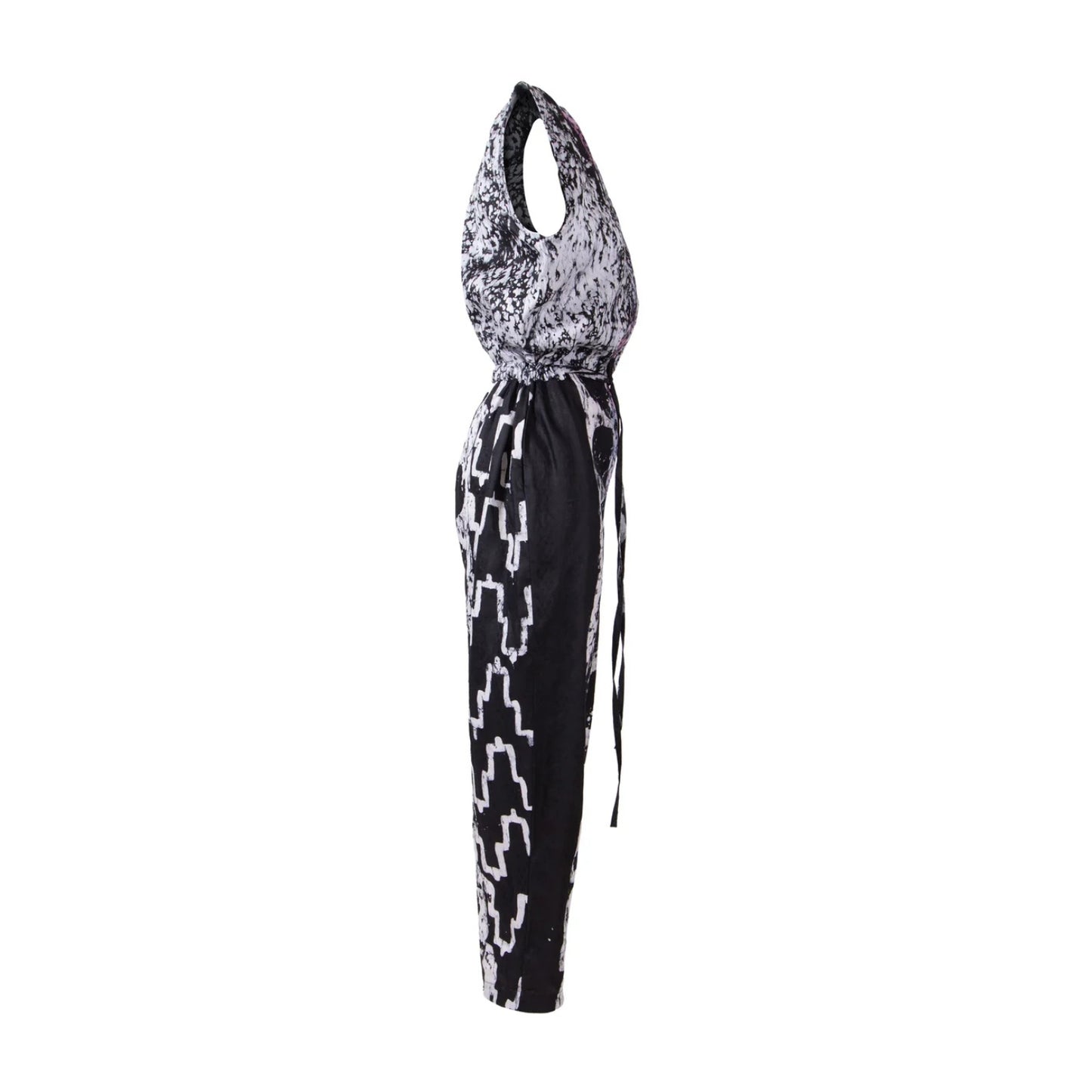 A sleeveless halter-neck jumpsuit with a black and white abstract pattern, featuring a tie-waist detail and geometric print on the legs, shown against a plain white background.
