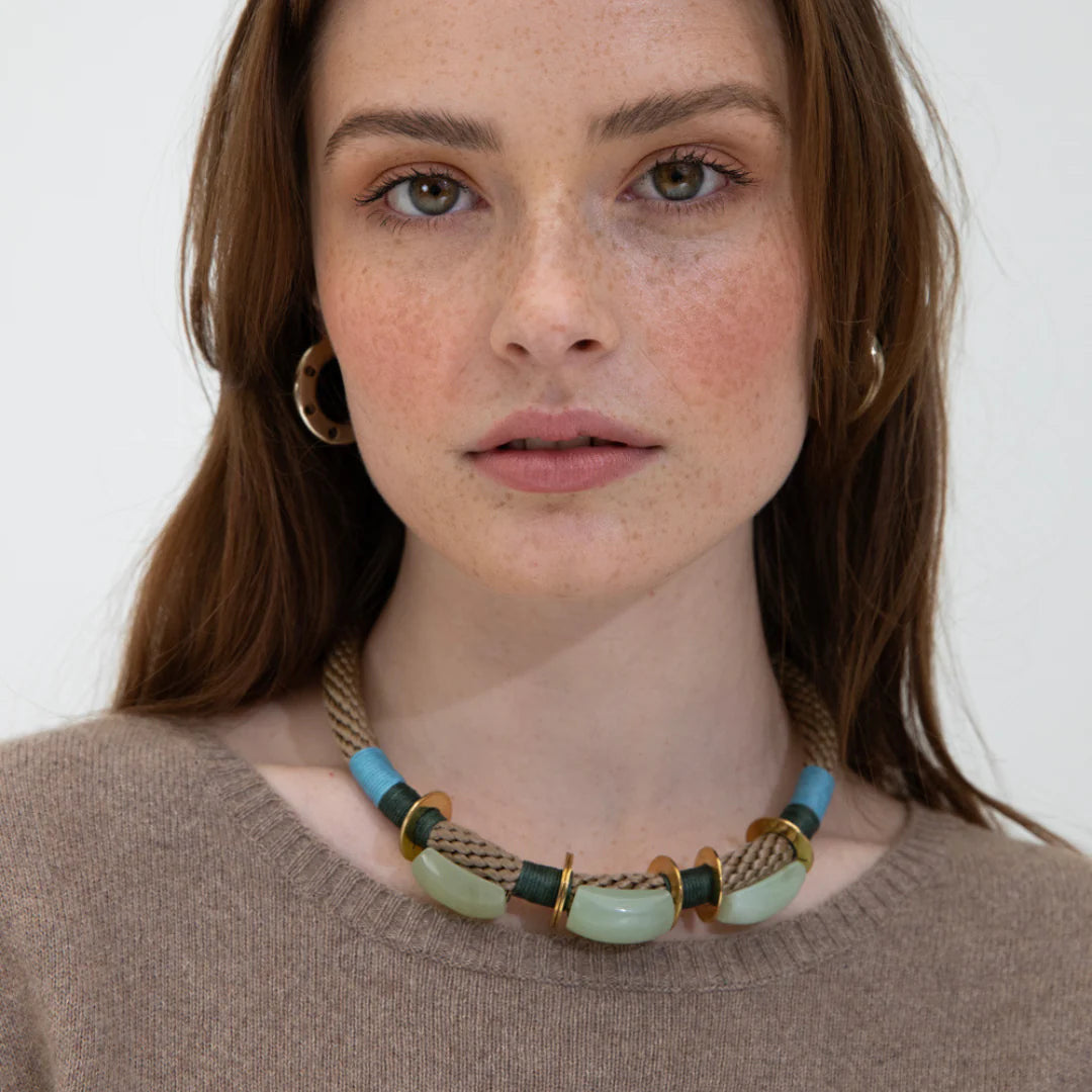 Woman wearing a necklace with beads on a plain background