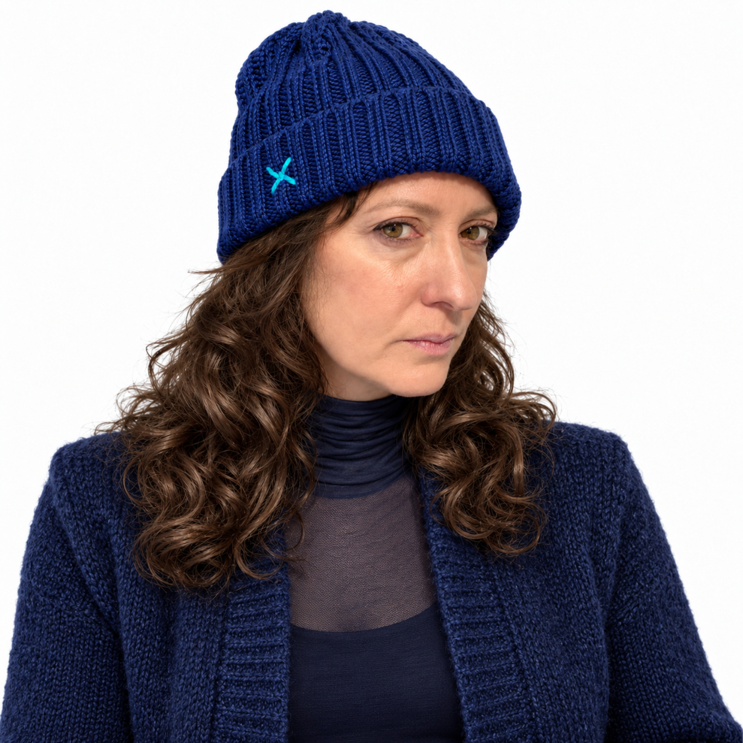 A woman wearing a navy blue ribbed knit beanie with a small light blue embroidered logo, paired with a matching navy cardigan and dark top, against a plain white background.