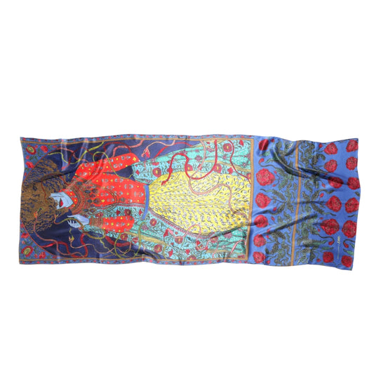 A rectangular silk scarf featuring a highly detailed, colorful tapestry-style print with a central figure, floral motifs, and ornate patterns in blue, red, yellow, and green, displayed flat against a white background.
