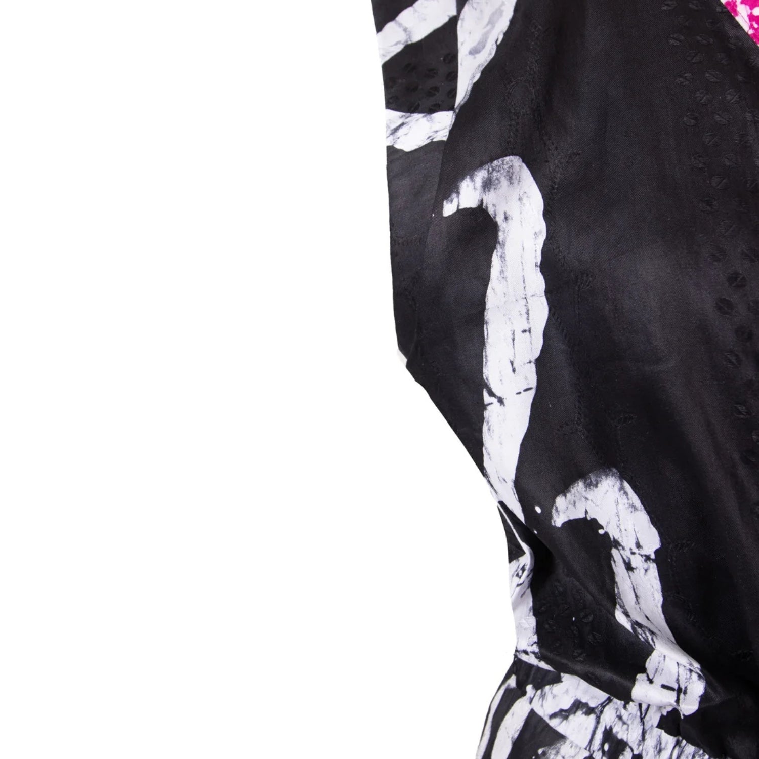 A close-up of a black garment with a bold white abstract brushstroke pattern, shown against a solid white background.