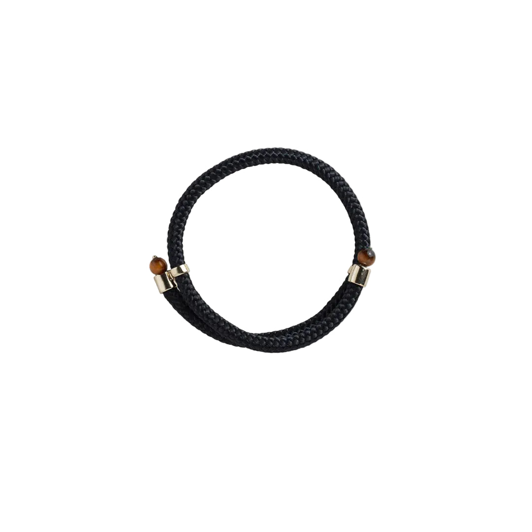 A black braided leather bracelet with gold-toned metal end caps and small brown beads, shown on a plain white background.