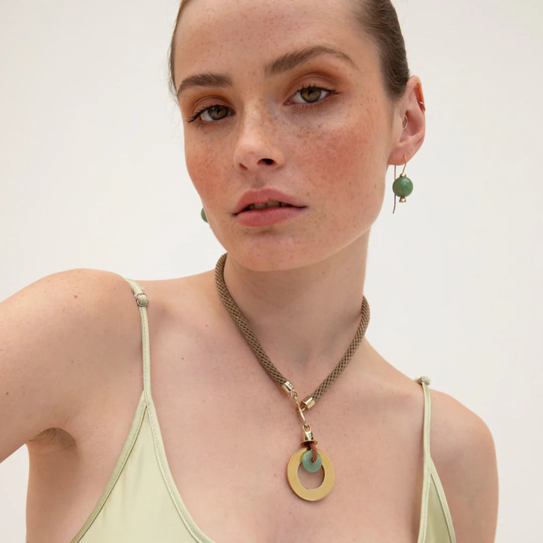 Woman wearing a necklace and earrings with a plain background