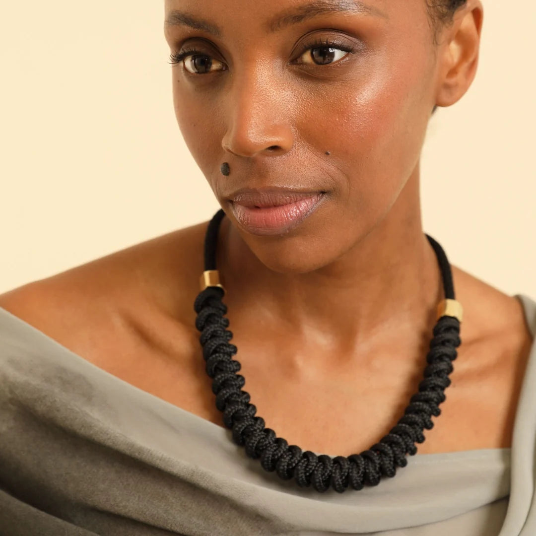 Woman wearing a black necklace against a beige background