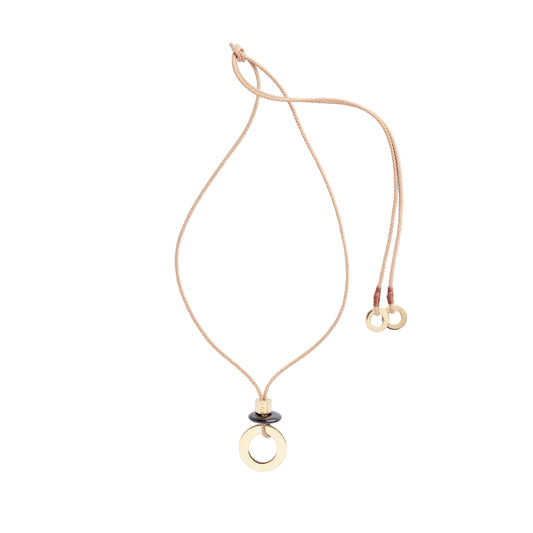 A thin, brass-colored rope necklace with a round obsidian pendant and two brass disc caps.