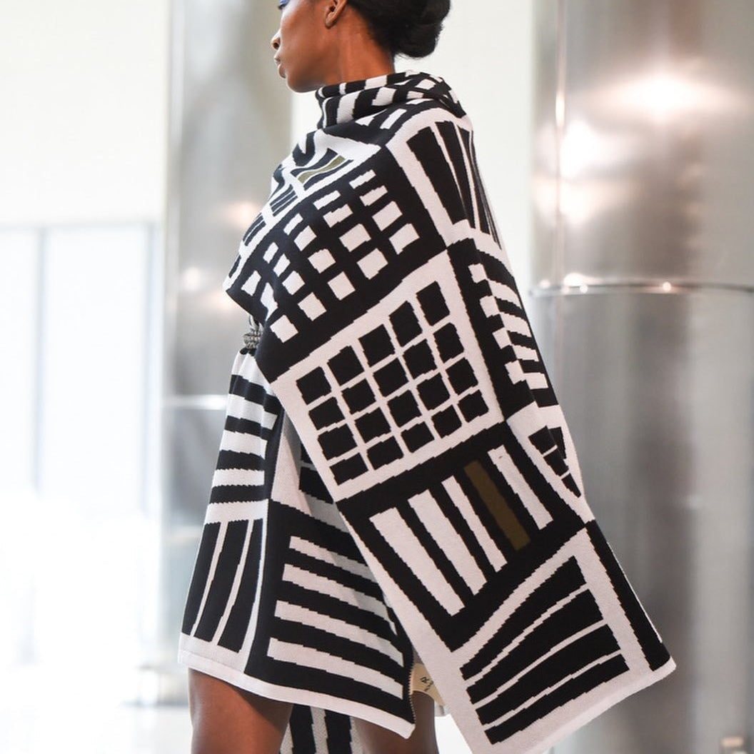 Person wearing a black and white patterned coat in an indoor setting