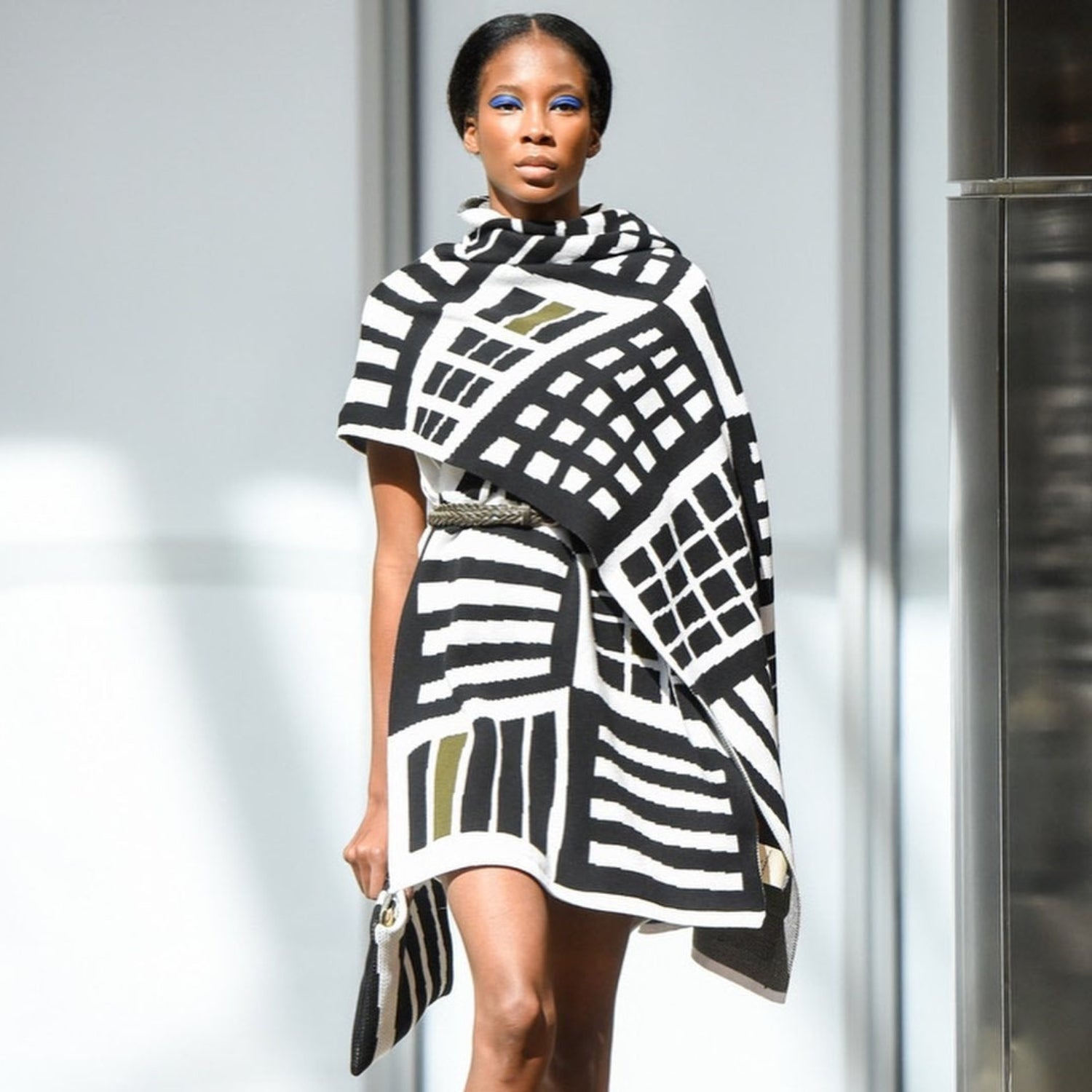 Model wearing a black and white patterned dress against a neutral background