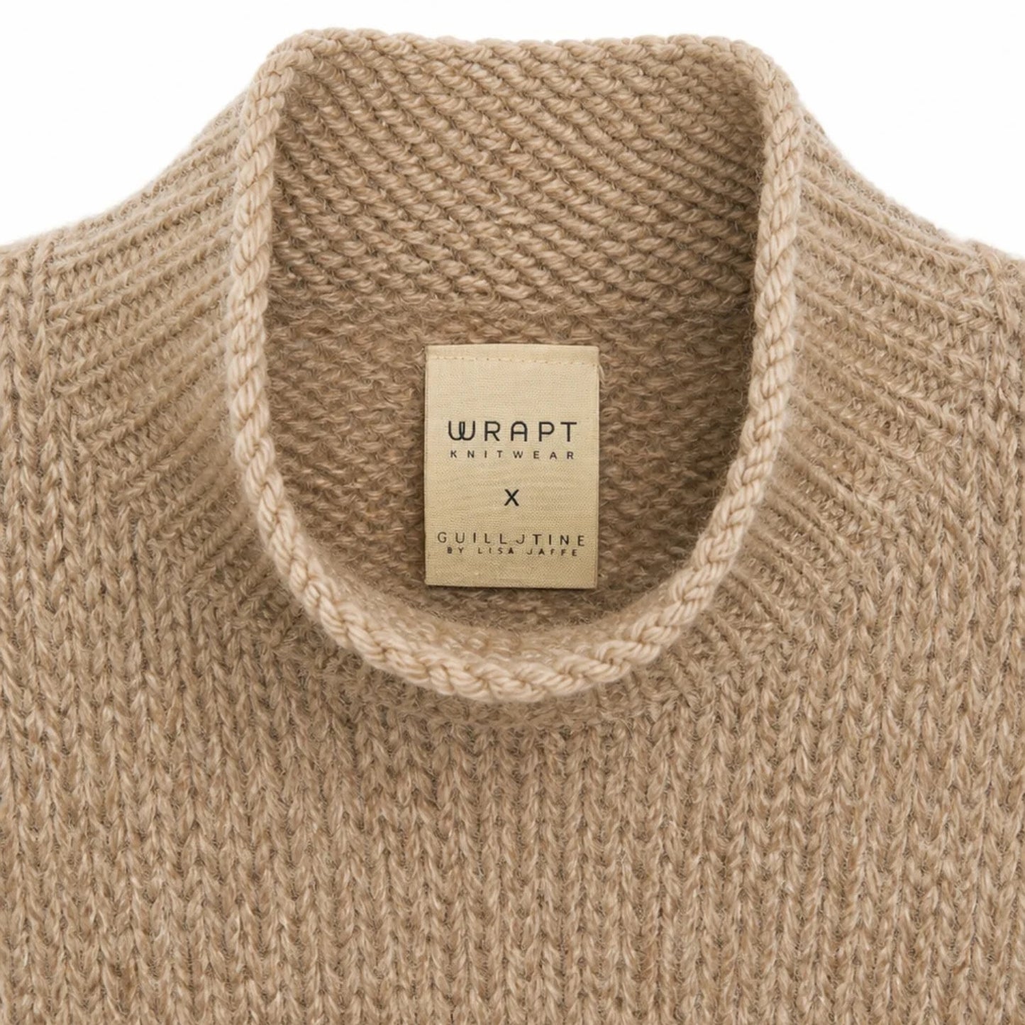 Close-up of a beige knit sweater collar with a visible neck label reading WRAPT Knitwear x Guillotine by Lise Jacobs.