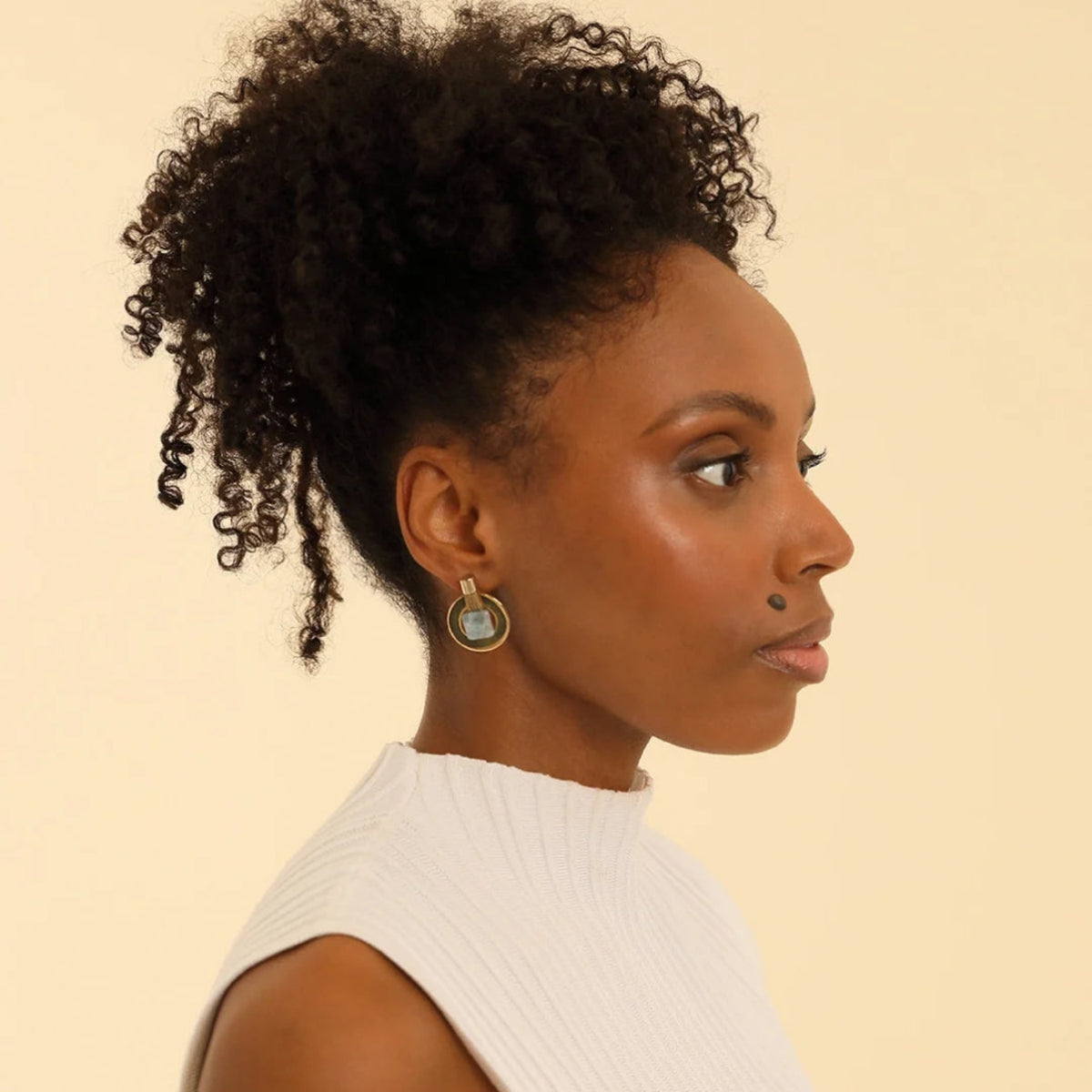 Woman with styled hair against a beige background