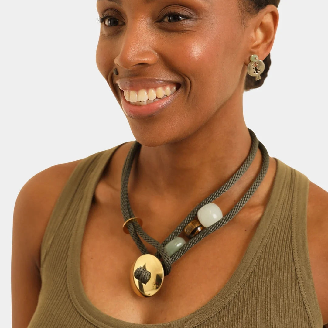 Woman wearing a necklace with multiple pendants on a plain background