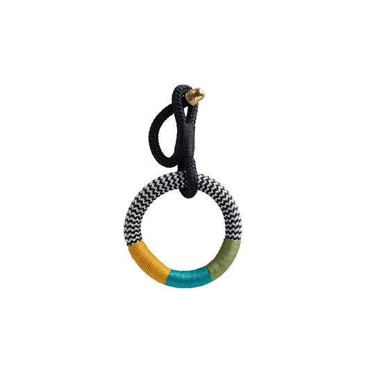A multicolored geometric patterned keyring with a rope and brass enclosure, featuring wax cotton embellishments.